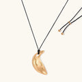 Gold crescent moon pendant with paisley patterns on adjustable black cord with brass beads
